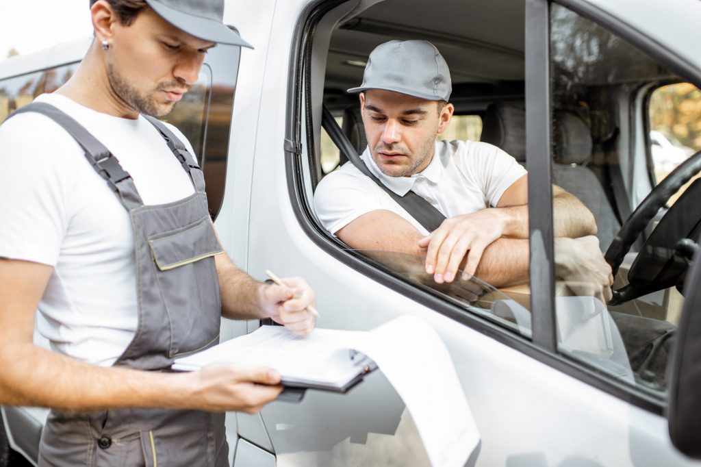 Man in work van talking to a colleague stood outside