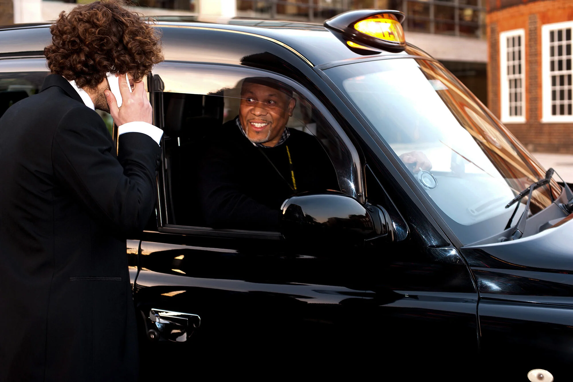 Taxi driver talking to a passenger outside his vehicle