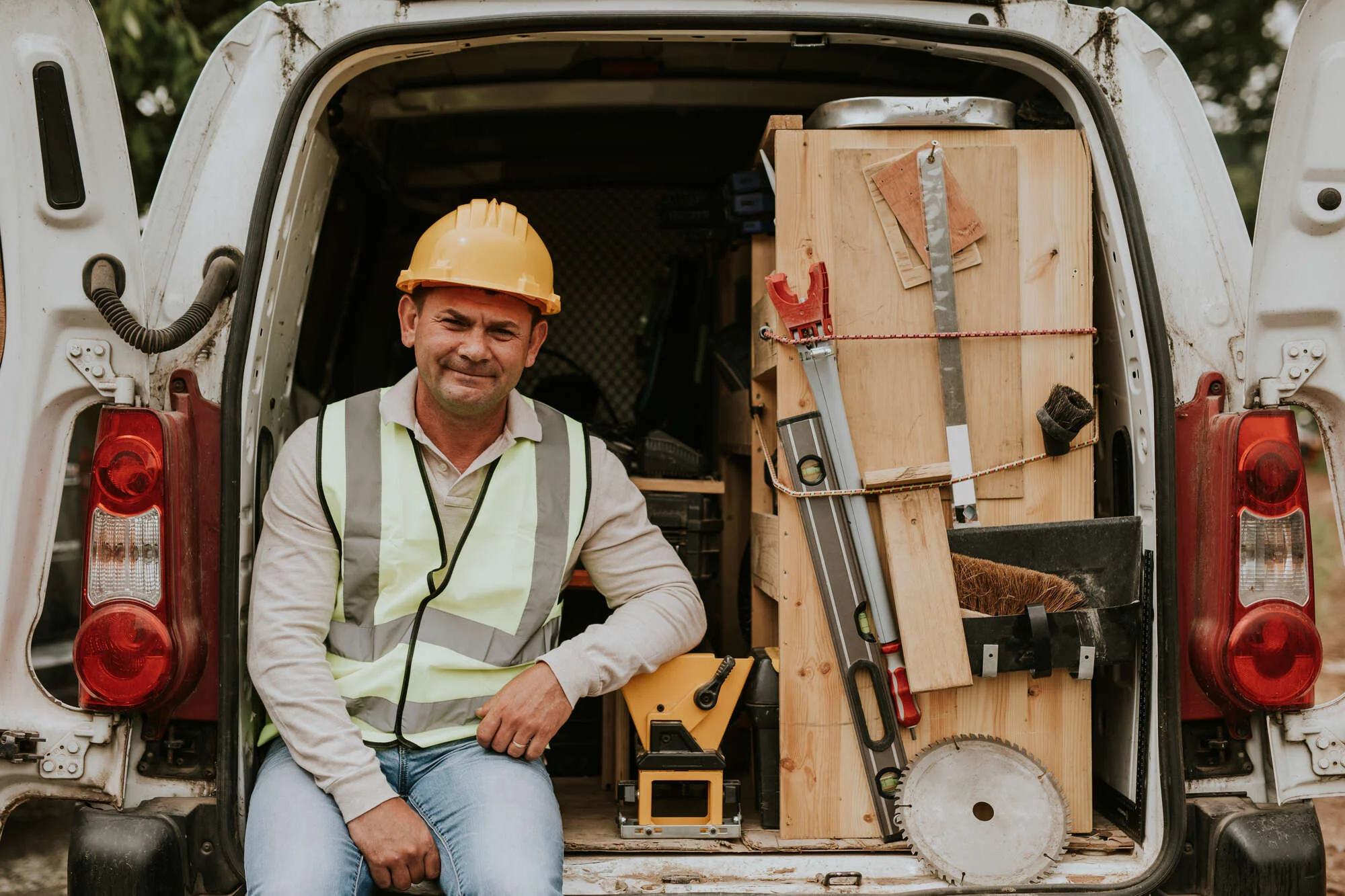 Builder sat in the back of his work van next to his tools