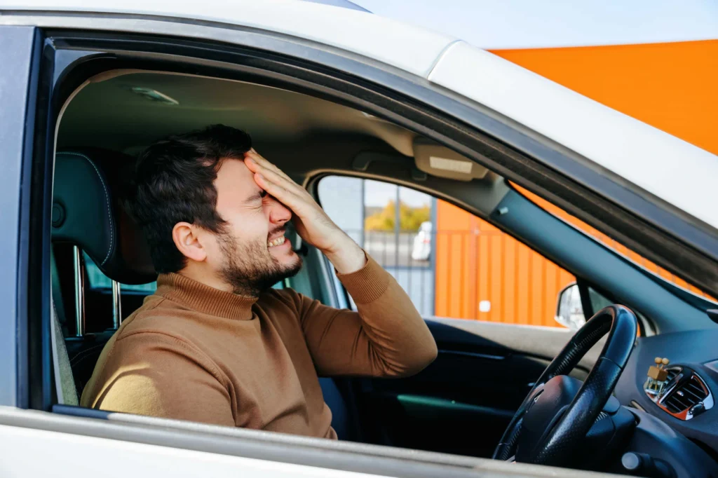 Parked driver looking frustrated with his head in his hands