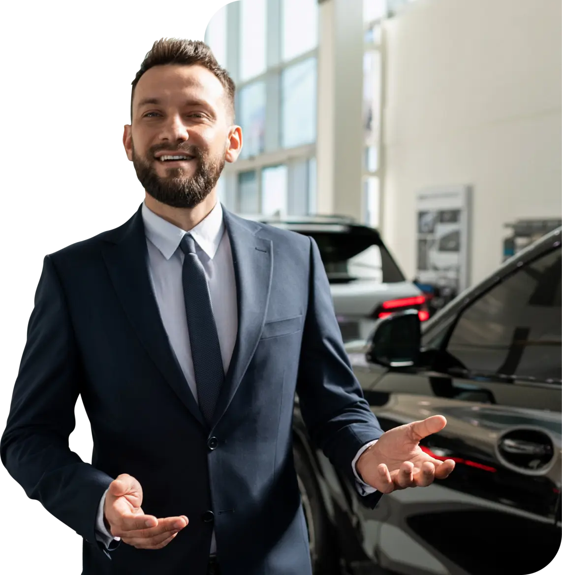 Car dealer stood in the showroom while smiling at the camera