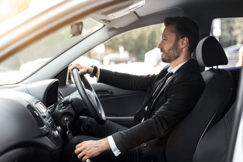 Image of a man driving a business car while listening to music